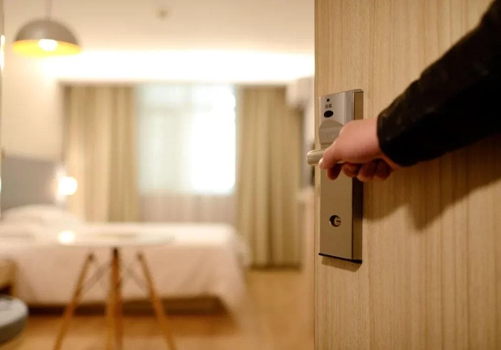 "Pessoa abrindo porta de quarto mobiliado em apartamento
